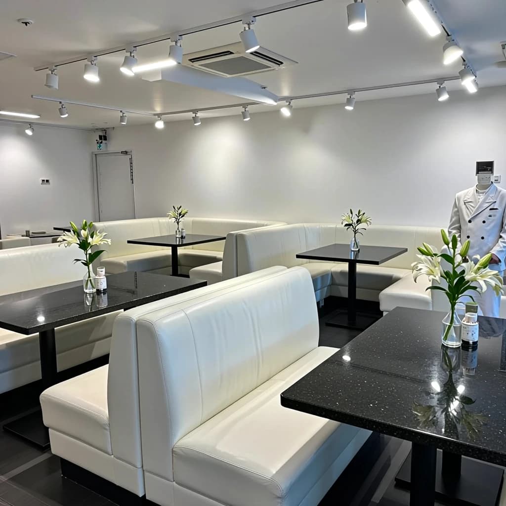 The place is almost empty. The banquettes are covered in white leather, the tables black granite, and the entire room is bathed in halogen track lighting that seems too bright. The maître d’ wears a double-breasted wool crepe jacket. There are lilies on every table.