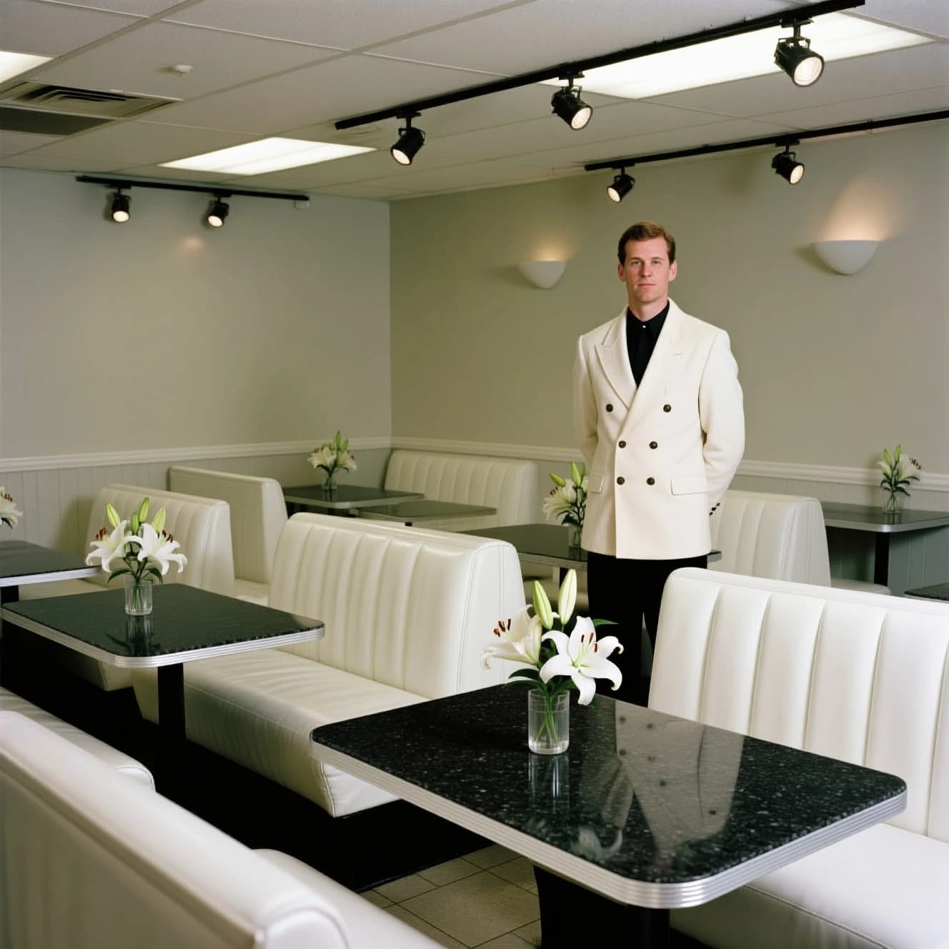 The place is almost empty. The banquettes are covered in white leather, the tables black granite, and the entire room is bathed in halogen track lighting that seems too bright. The maître d’ wears a double-breasted wool crepe jacket. There are lilies on every table.