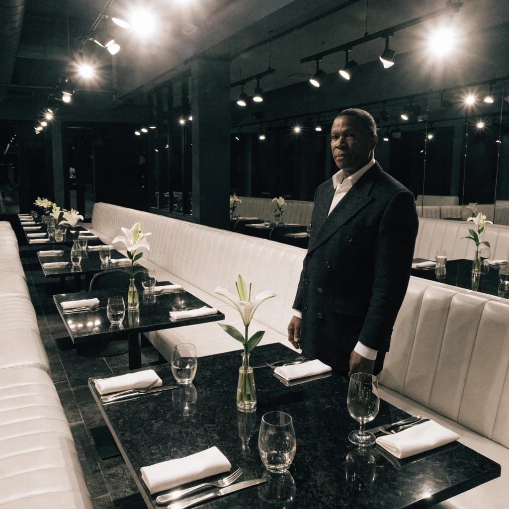 The place is almost empty. The banquettes are covered in white leather, the tables black granite, and the entire room is bathed in halogen track lighting that seems too bright. The maître d’ wears a double-breasted wool crepe jacket. There are lilies on every table.