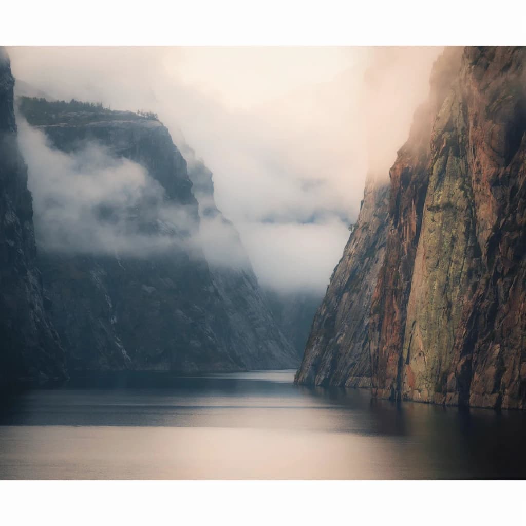 Frame a foggy fjord at sunrise, cliffs looming.