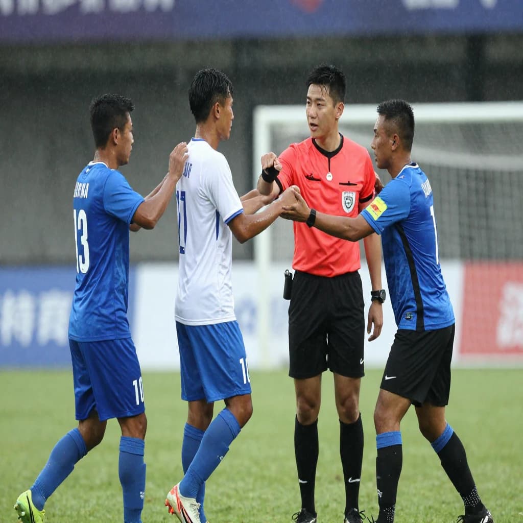 The soccer player clashes with the ref. It is thick and humid and the heat is getting to the players. His friend tries to pull him off before he causes any more trouble.